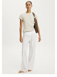Woman wearing cream t-shirt and white linen pants