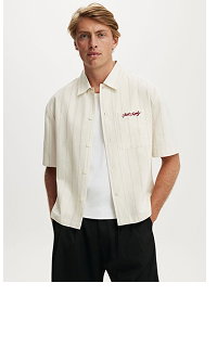 Man wearing cream short-sleeve shirt and black pants