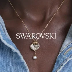 Halskette mit goldener Kette und Perlenanhänger in Form einer Muschel, getragen über dunkler Haut, kombiniert mit einem hellblauen Denimhemd.
