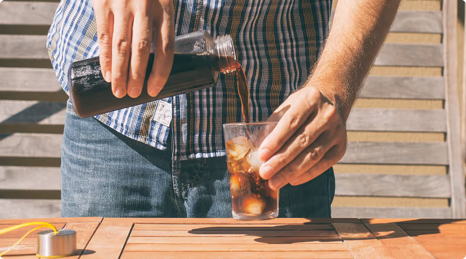 Person pouring a glass of Peet's iced coffee outside