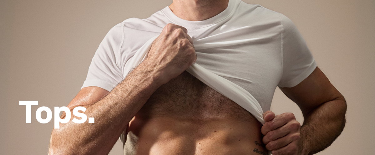 Model lifting white shirt to reveal SAXX top underneath with “Tops.” text overlay.