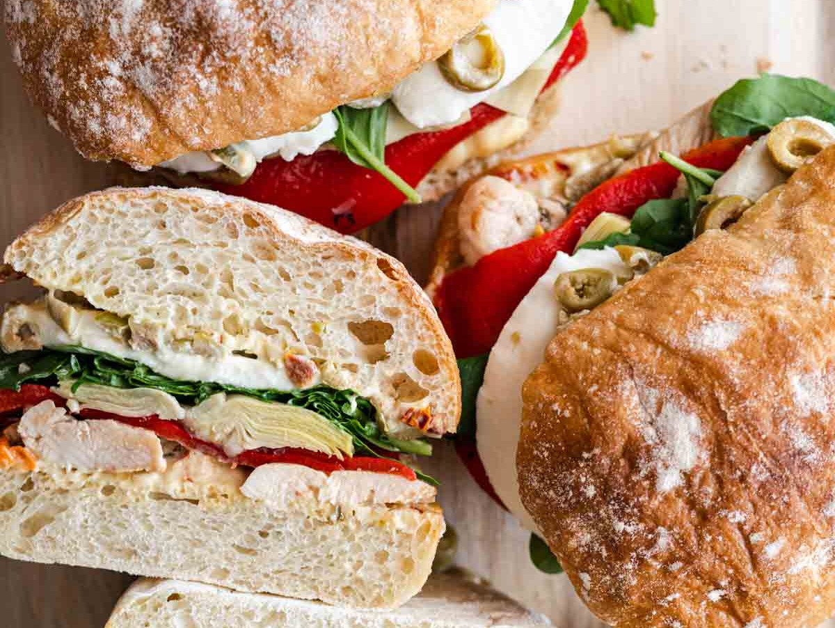 Several antipasto chicken sandwiches on a platter.