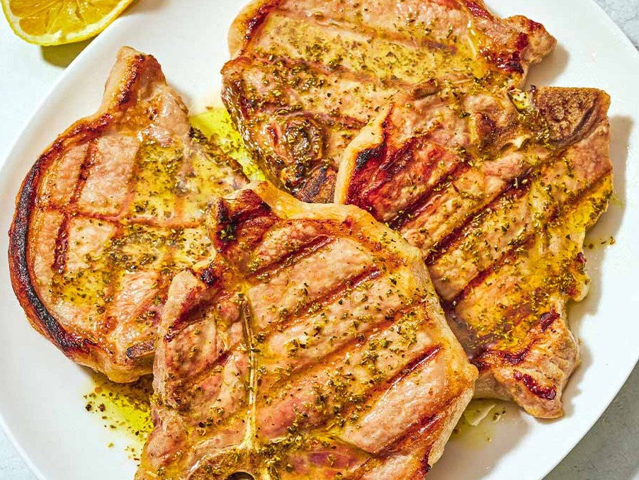 Four gilled pork chops on a platter.