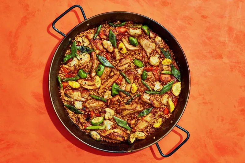 Skin-on chicken thighs, chanterelles, pattypan squash, carrots, cauliflower, romano beans, asparagus, paprika, grated tomatoes, saffron, chicken stock, rosemary, and Bomba rice cooked in a paella.
