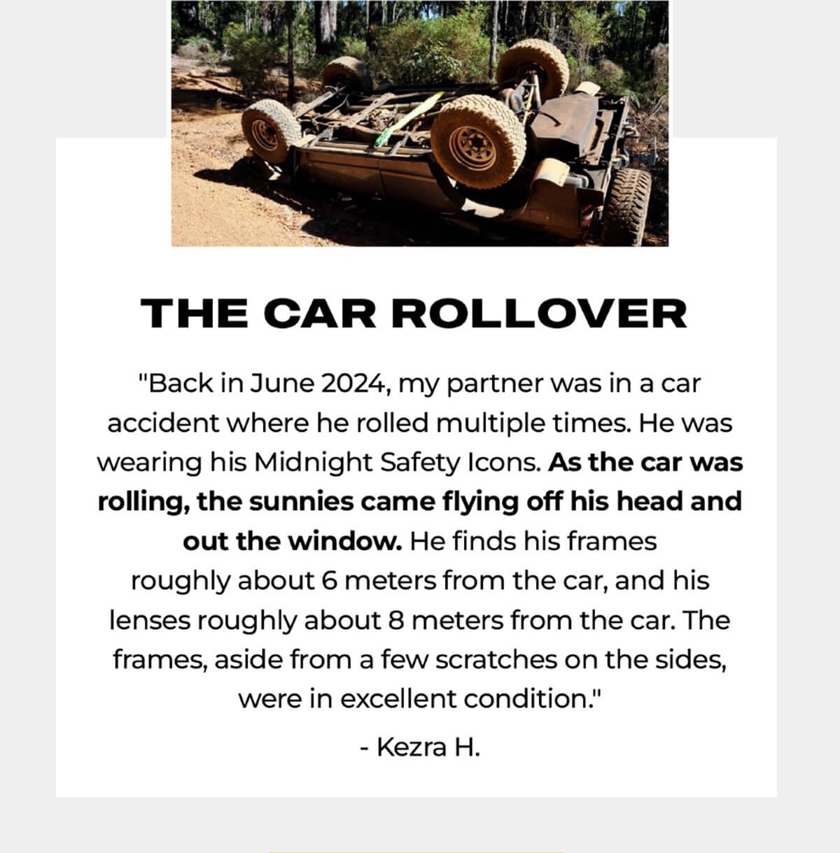 Overturned military-style vehicle with large wheels on dirt ground surrounded by trees and vegetation