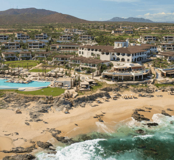 Coastal resort with luxurious villas and pool overlooking a sandy beach.