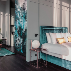 A luxury hotel room featuring turquoise accents and plush King size bed.