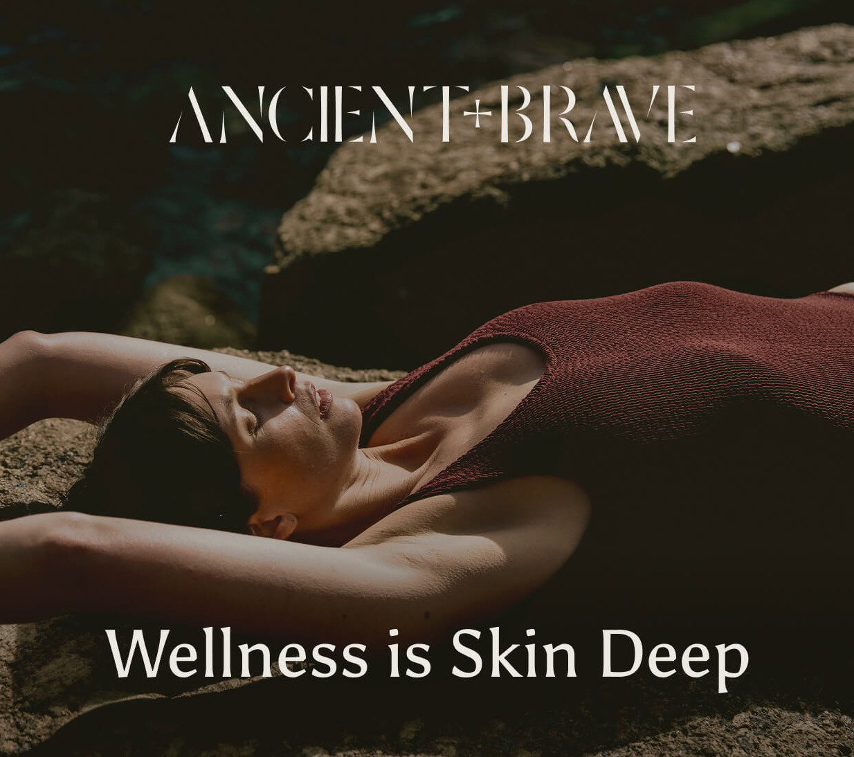Woman stretches in a swimsuit while laying on the sand. The words overlaid read 'Wellness is skin deep'.