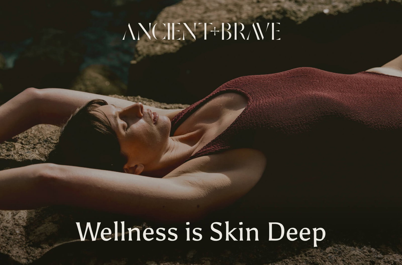 Woman stretches in a swimsuit while laying on the sand. The words overlaid read 'Wellness is skin deep'.