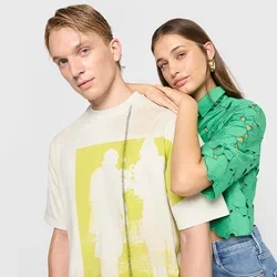Grafisches T-Shirt in Creme mit gelber Druck; kurzärmeliges grünes Oberteil mit Blumen-Ausschnitten. Beide kombiniert mit blauen Jeans.