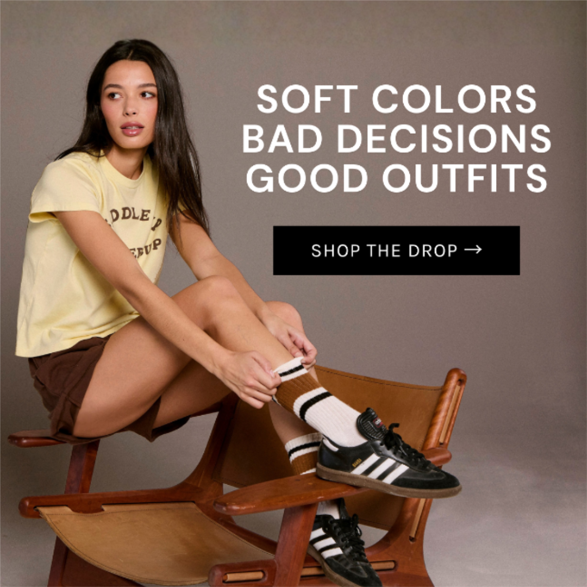 Chaser Summer 2026 graphic tee in Blonde styled with brown shorts, striped socks, and sneakers in an editorial studio setting inspired by vintage roadside Americana