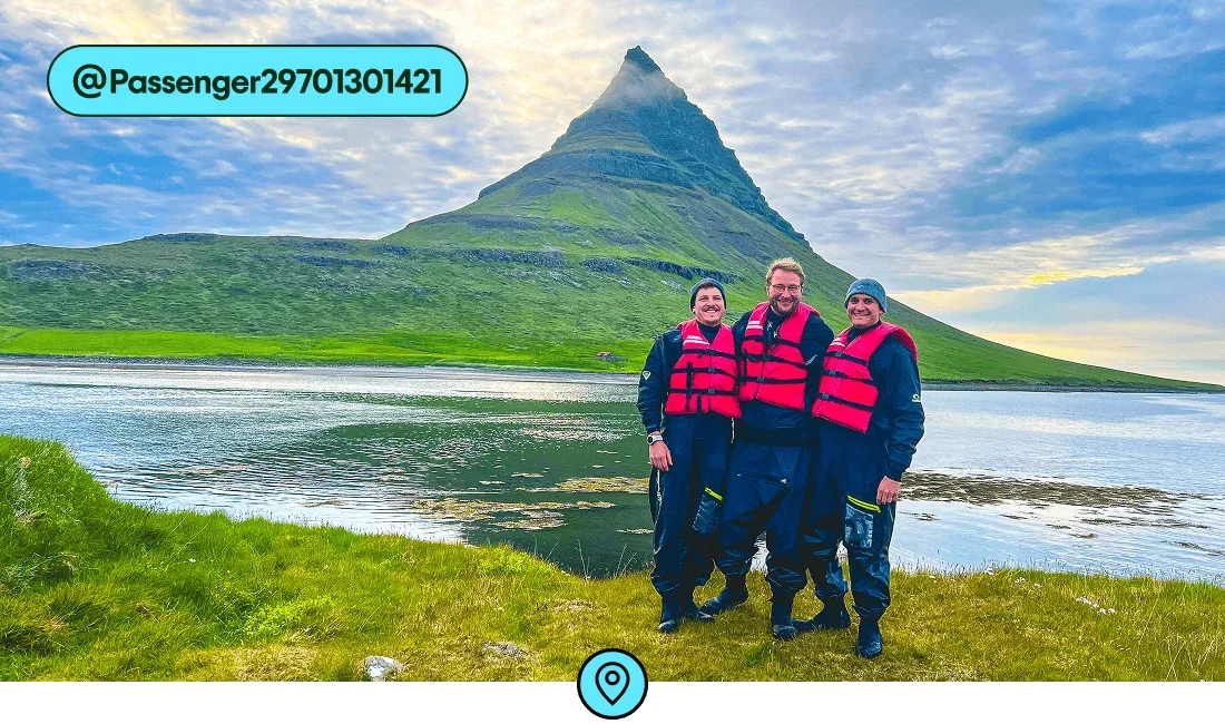 Image description: Three people with red lifevests posing in front of the Kirkjufell mountain, photo taken by @Passenger29701301421