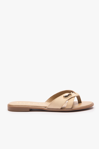 Beige flat sandal with criss-cross straps and gold buckle detail on white background