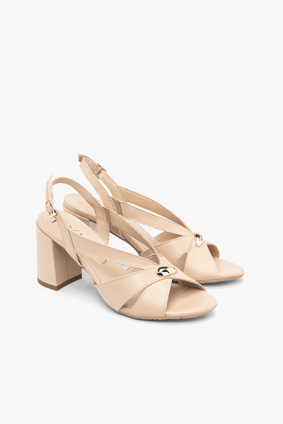 Beige high-heeled sandals with ankle straps and gold buckle detail on white background