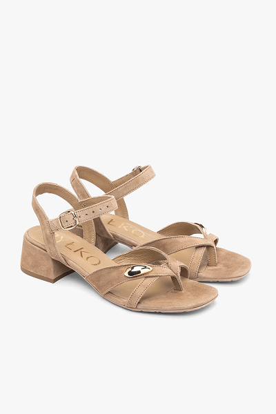 Beige strappy sandals with low block heels and buckle detail on white background.