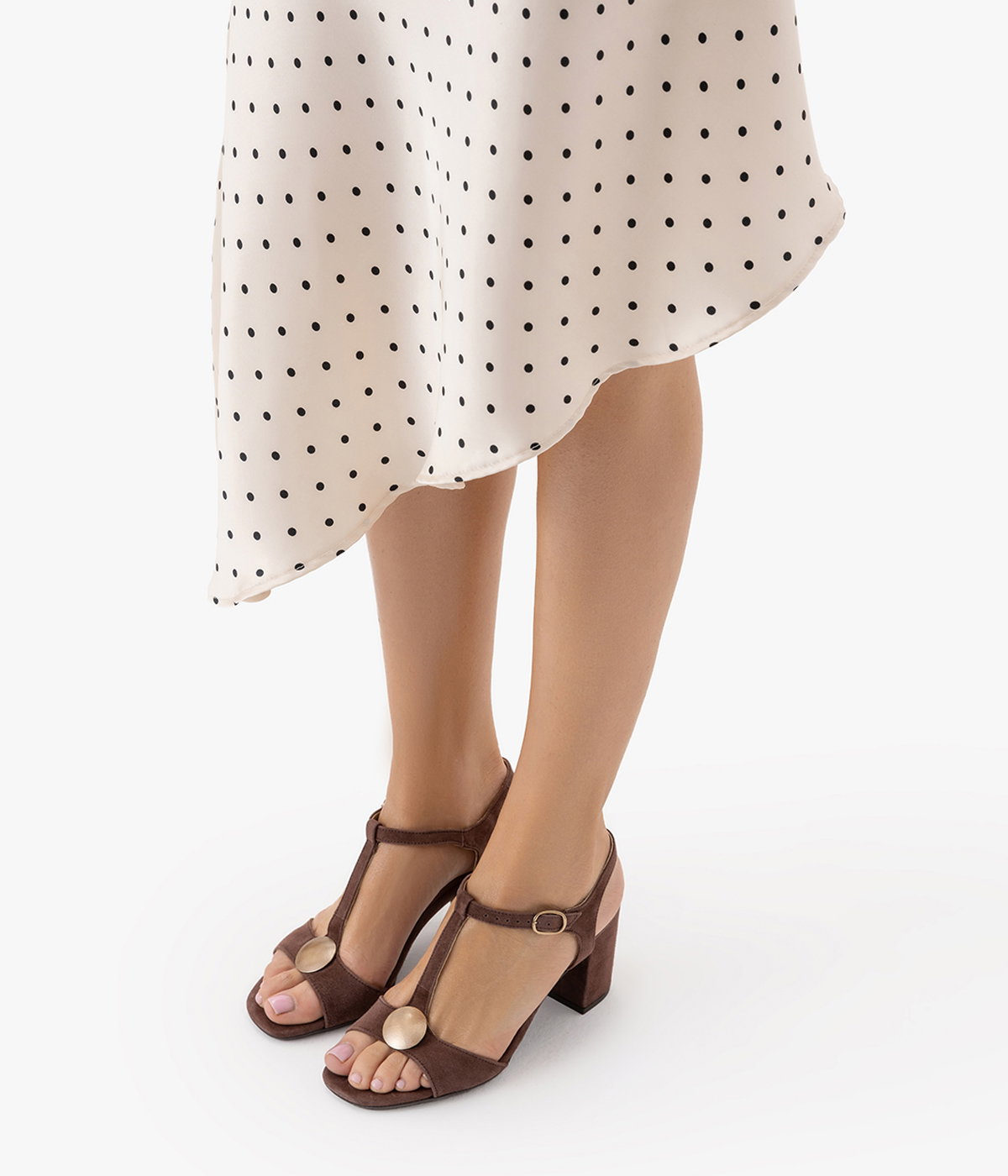 Woman wearing polka dot dress and brown high-heeled sandals with gold accents