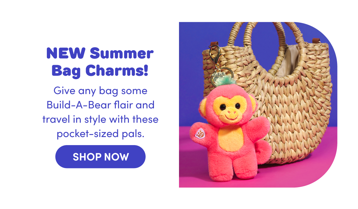 Bold blue headline text reads NEW Summer Bag Charms! with supporting text Give any bag some Build‑A‑Bear flair and travel in style with these pocket‑sized pals. A blue SHOP NOW button appears below. On the right, a bright pink Mango Monkey plush bag charm with a smiling face hangs from a gold key ring clipped to a woven straw tote, set against a purple and pink surface, highlighting the colorful, pocket‑sized summer accessory.