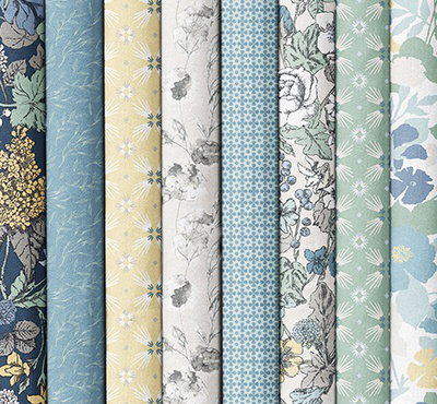 Folded fabrics in blues, creams, and greens with various floral patterns. >>