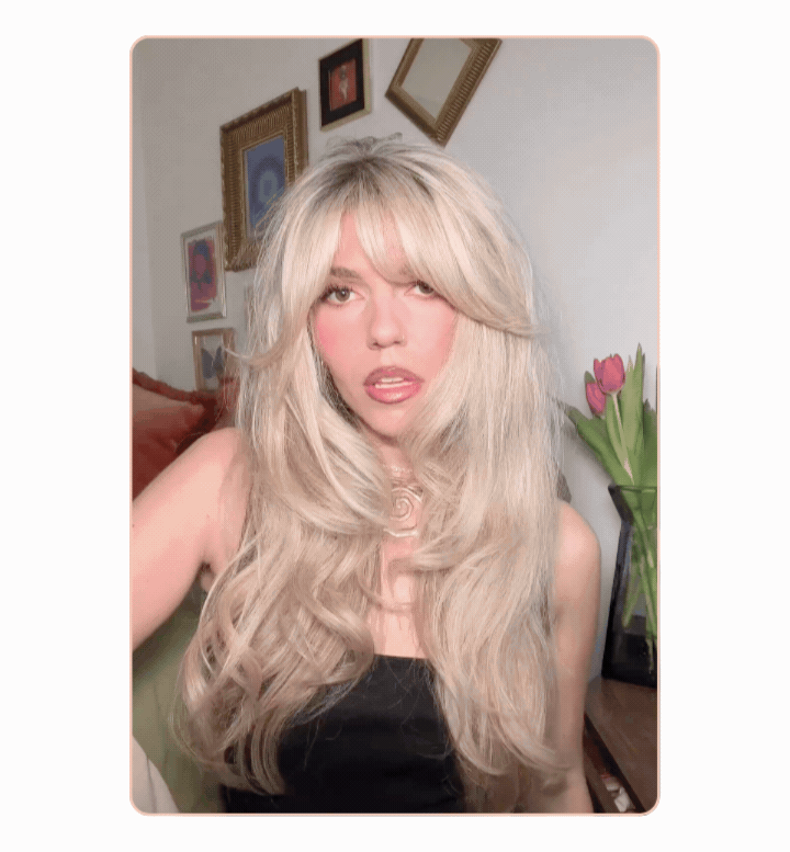 Animated image of a woman with long, voluminous blonde hair styled in a layered blowout with curtain bangs. The image highlights smooth texture, body, and movement for a salon-inspired summer hairstyle.
