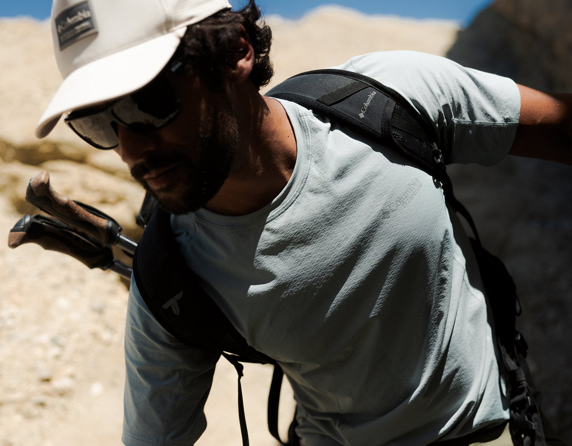 Close up of man hiking on a rocky mountain with his Columbia gear on.