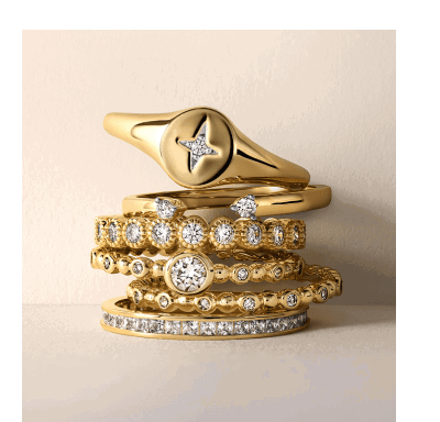 Stacked yellow gold rings with diamond eternity bands and signet ring.