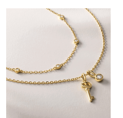 Layered yellow gold necklaces with key charm pendant and bezel-set diamond accents.