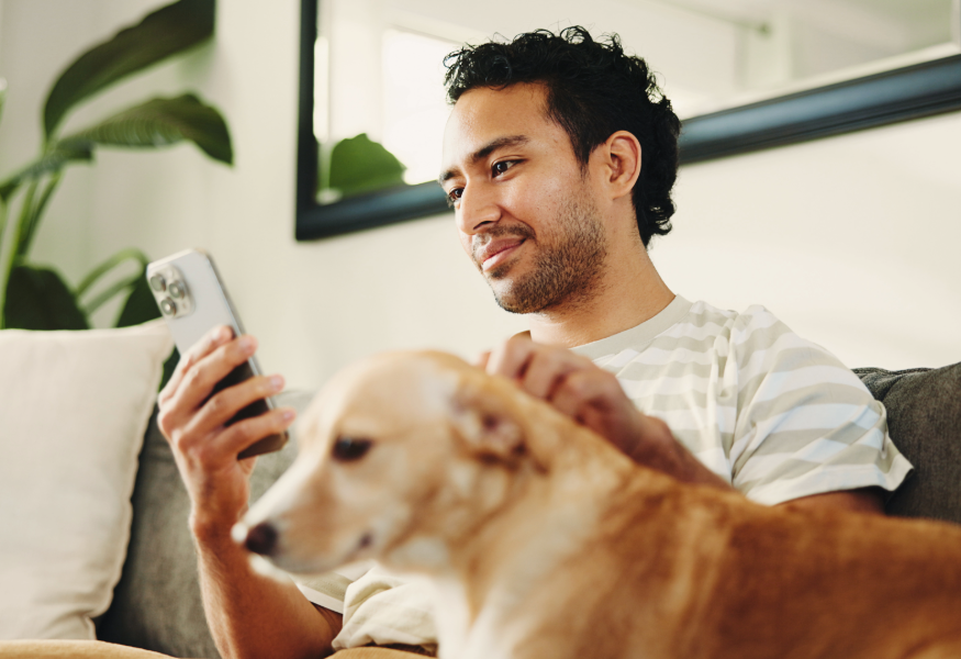 Man sitting with a dog, checking his phone