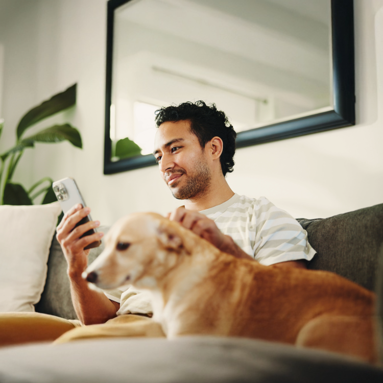 Man sitting with a dog, checking his phone