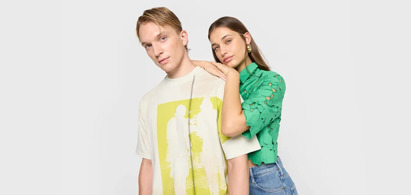 T-shirt graphique crème avec imprimé jaune ; haut vert à manches courtes avec des découpes florales. Les deux sont assortis à un jean bleu.