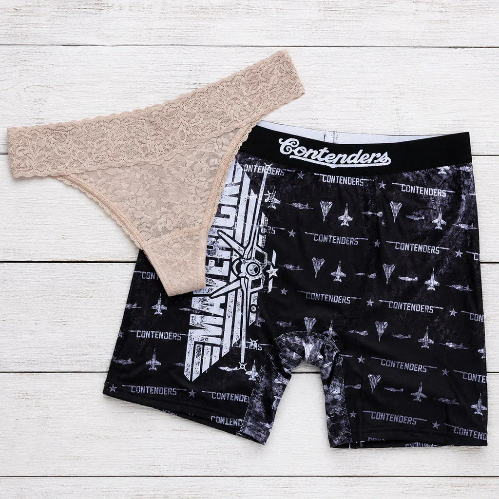 Two pairs of underwear displayed on white wood: beige lace thong and black patterned boxer briefs with 
