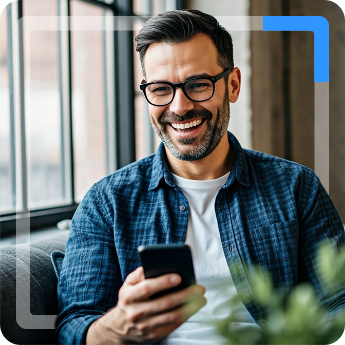 Glimlachende man met bril die naar zijn telefoon kijkt in een modern interieur