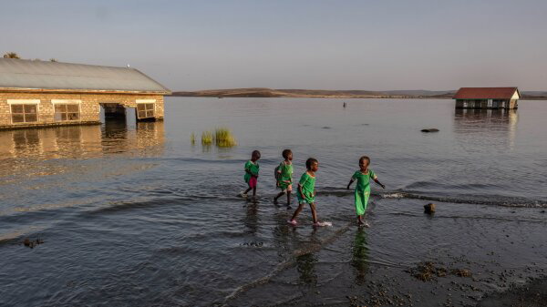 School children walk through the shallows past submerged and abandoned school buildings at the El Molo Bay primary school in Komote, Kenya. 