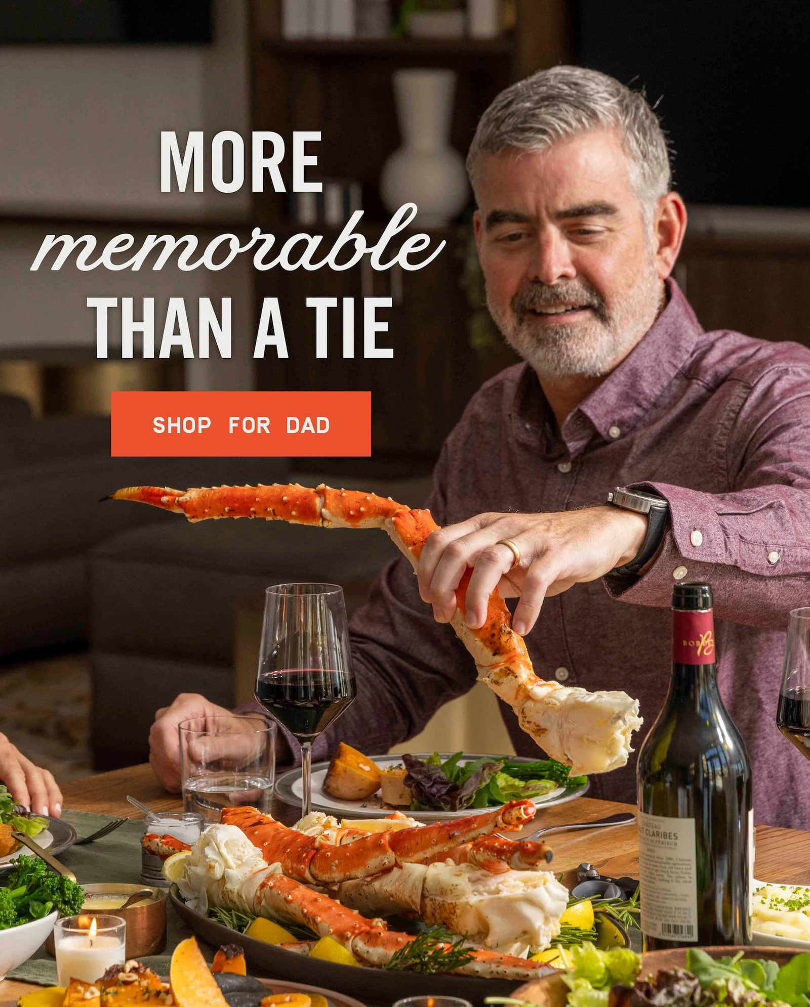 Man holding a large king crab leg at a table.