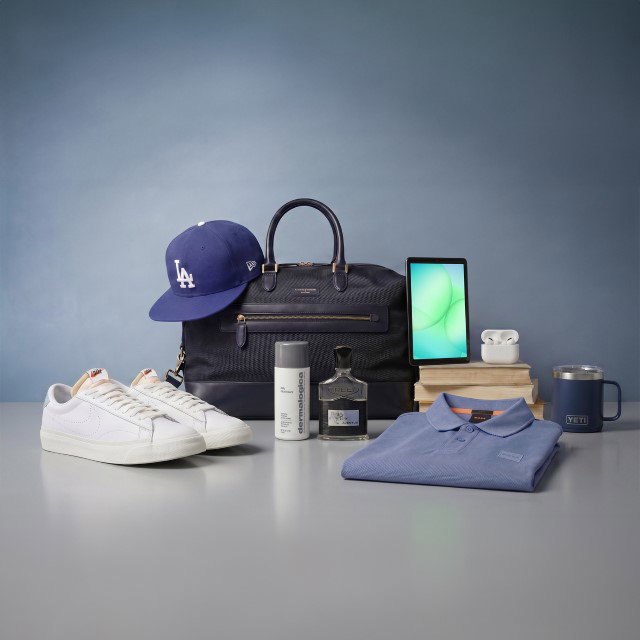 Collection of items including a blue cap, white sneakers, navy bag, smartphone, skincare products, blue polo shirt, books, and a mug on a table.