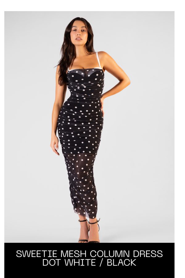 Model wearing a black and white polka dot dress with a fitted silhouette.