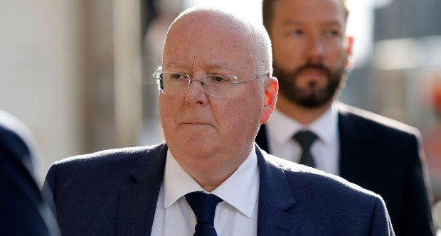 Peter Murrell, who is bald with glasses, in a close-up shot while walking outside. He is wearing a business suit