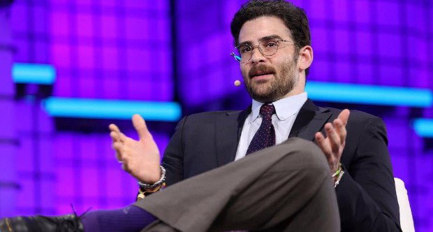 Left-wing streamer Hasan Piker speaking while seated. He is smartly dressed, wears glasses and has a beard.