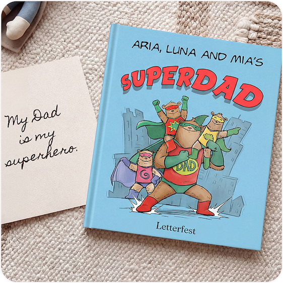 A personalised Superdad book titled "Aria, Luna and Mia's Superdad" displayed on a woven rug alongside a handwritten note