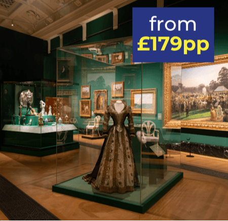 A museum interior featuring a historical dress in a display case, surrounded by art and artefacts.