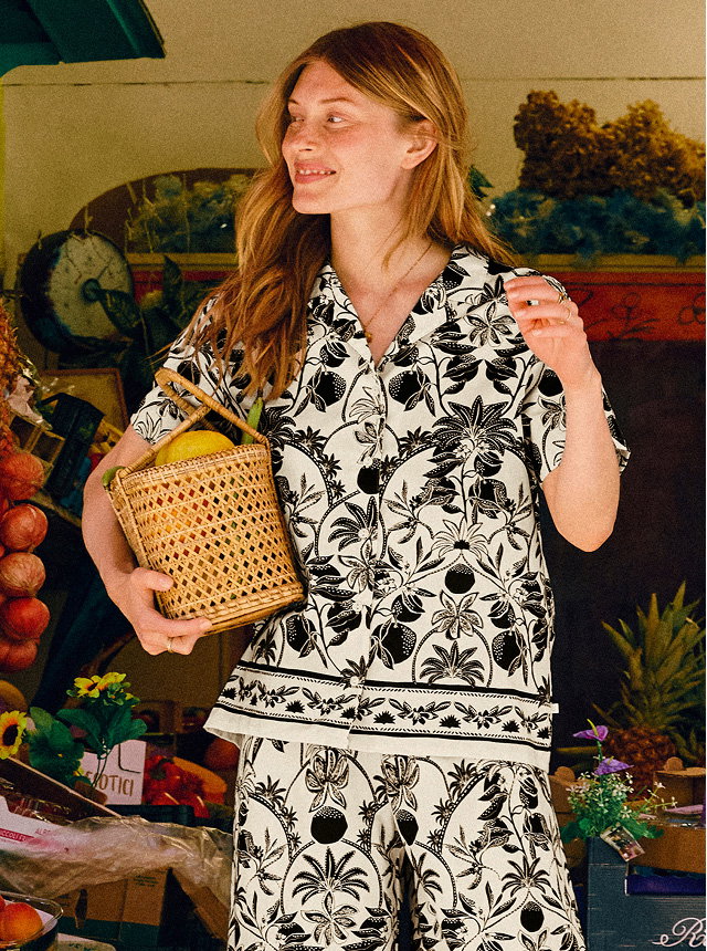The model is wearing a patterned short-sleeved shirt with buttons and the matching 7/8 pyjama trousers in the colour Charm Cream from the Favourites Layering series by CALIDA.