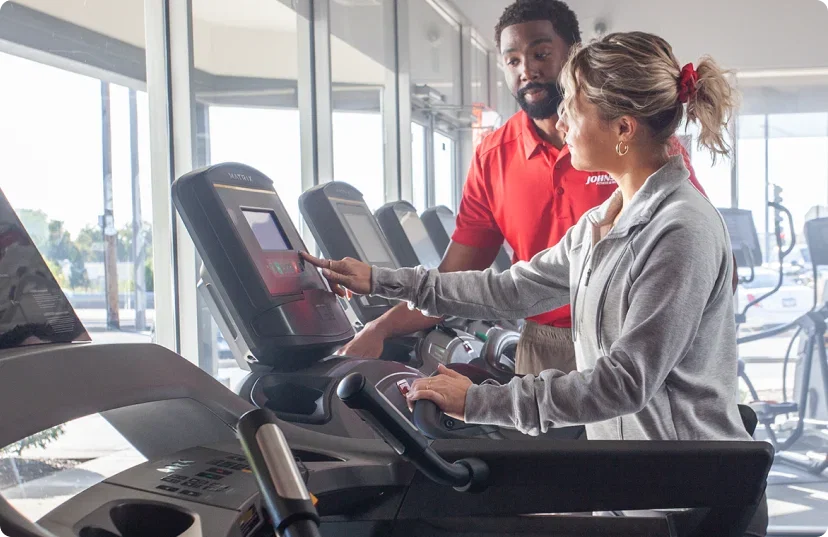 Sales associate showing female customer treadmill selection in JFW showroom