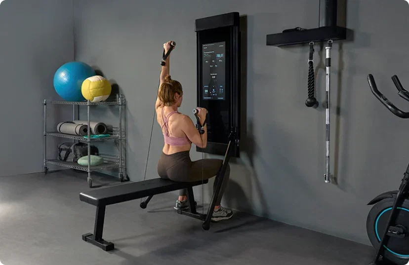 Woman doing seated exercises with Tonal 2 Smart Home Gym in home garage
