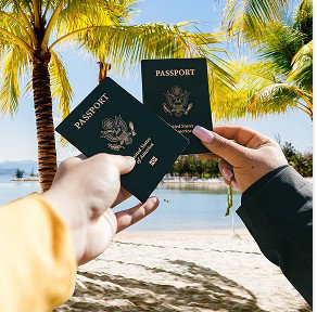 Two people hold up U.S. passports on a sunny beach with palm trees in the background.