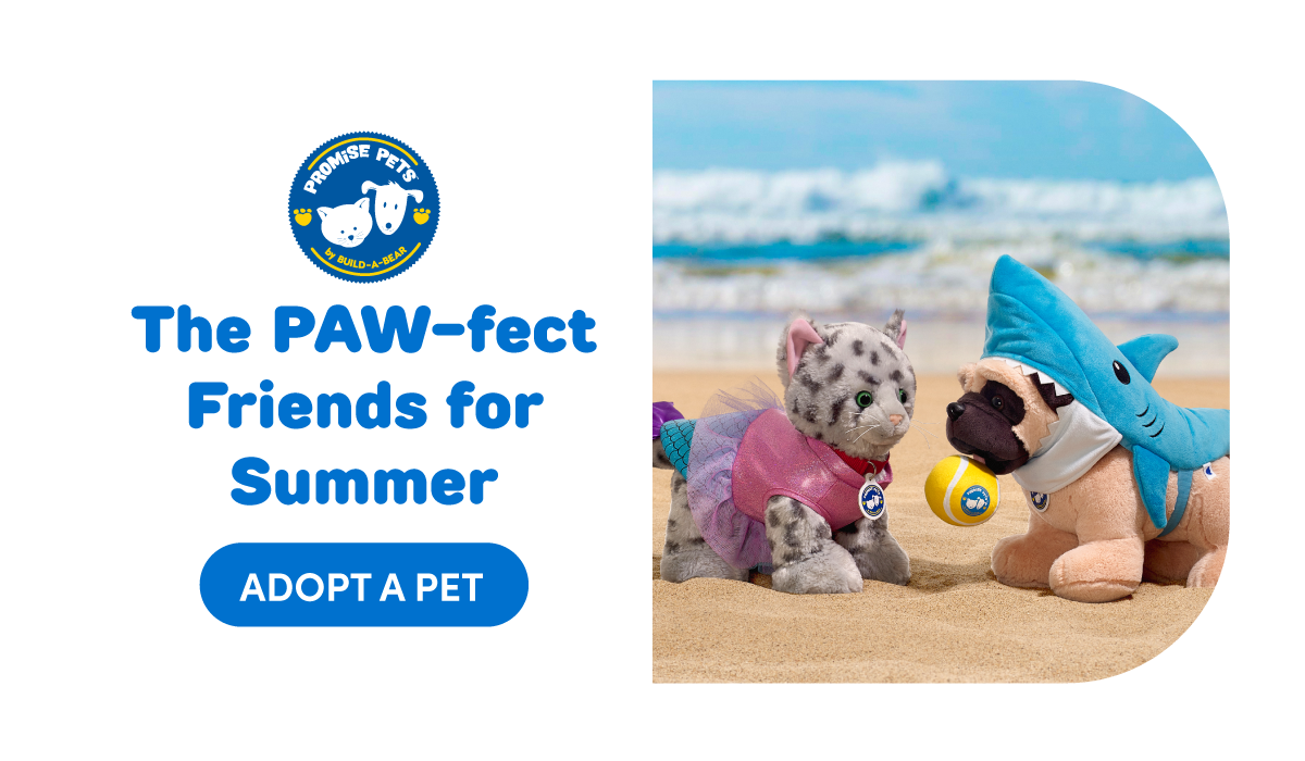 Split layout beach scene with ocean waves and sandy shore. On the right, two Promise Pets plush sit facing each other: a spotted grey cat wearing a pink top with mermaid tail fin detail and a tan dog wearing a blue shark costume holding a yellow ball. On the left, a blue Promise Pets by Build-A-Bear logo appears above headline text. Text reads: The PAW-fect Friends for Summer Adopt a Pet