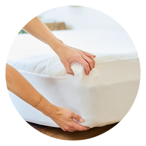 A woman placing a Performance Mattress Protector on a mattress