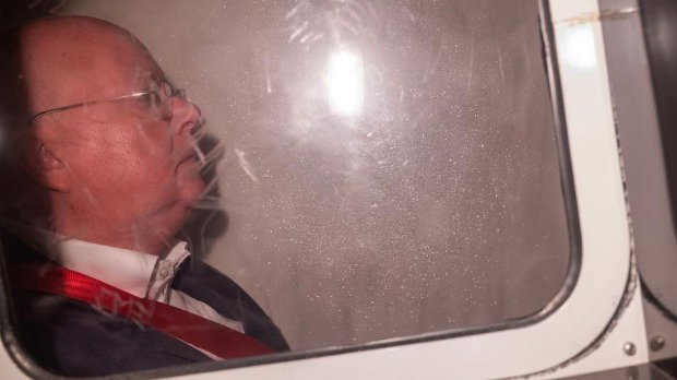 A picture of Peter Murrell in the back of a police van, wearing a suit and glasses.