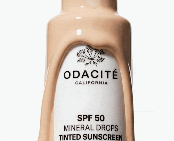  Close-up of Odacité SPF 50 Mineral Drops Tinted Sunscreen bottle with liquid product flowing over the exterior