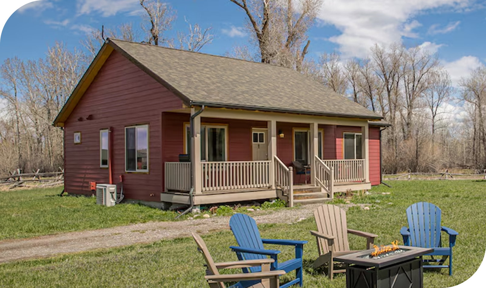 Cozy red cottage with front porch, fire pit seating, and open grassy yard.