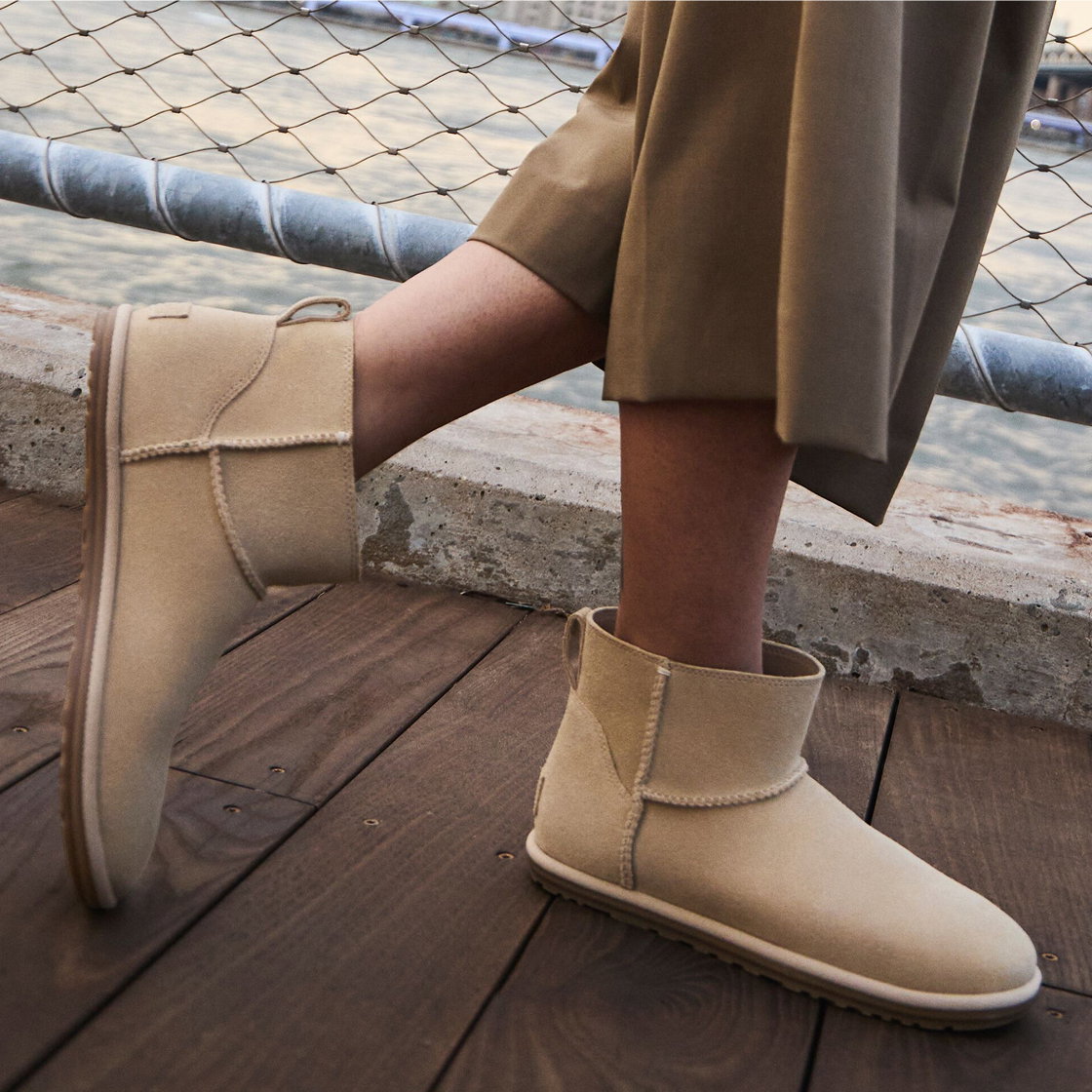 A close up of a person's legs wearing the Classic Mini, walking across a bridge.