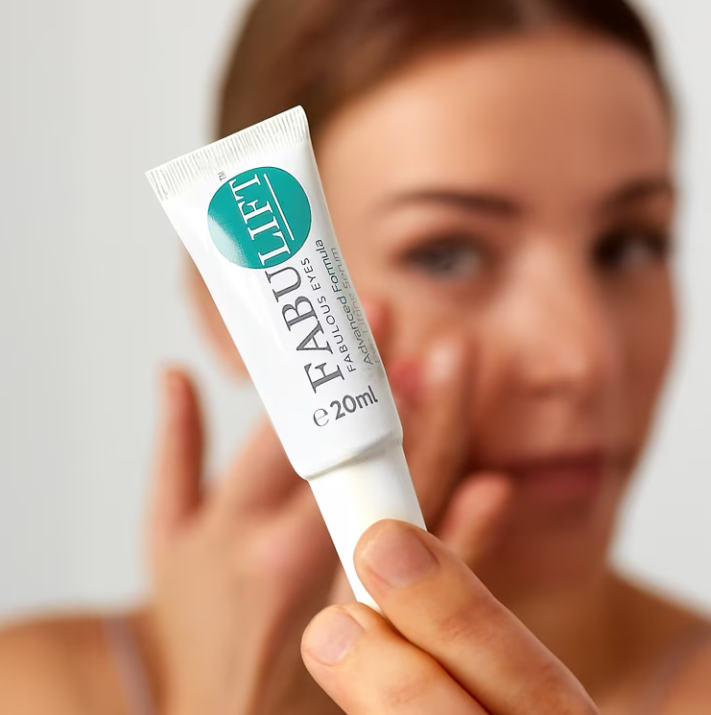 an image of a woman holding a tube of toothpaste in her hand